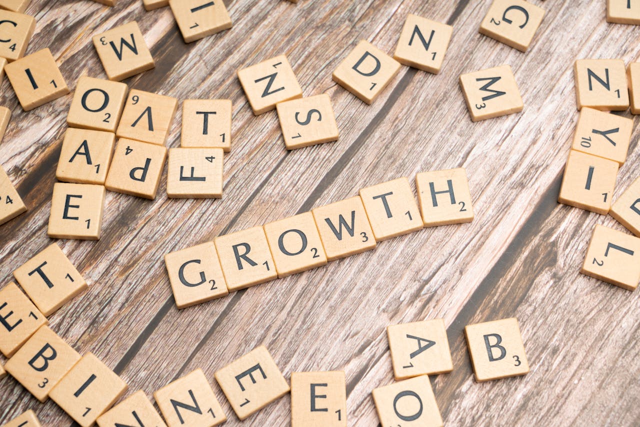 Scrabble tiles spelling growth on a wooden surface symbolize progress and expansion.